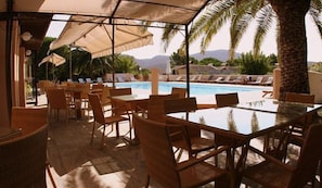 A poolside area with outdoor seating and umbrellas.