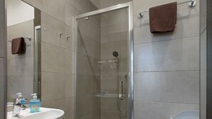 Ein modernes Badezimmer mit einer Duschkabine, einem Waschbecken mit Spiegel und einer Toilette.