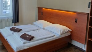 Ein Einzelbett mit Holz Kopfteil, weißer Bettwäsche und zwei braunen Handtüchern.