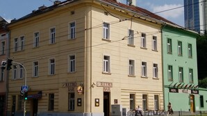 Ein gelbes Gebäude mit einer Bar namens 'Retro' und einem Hostel namens 'Hello Prague'.
