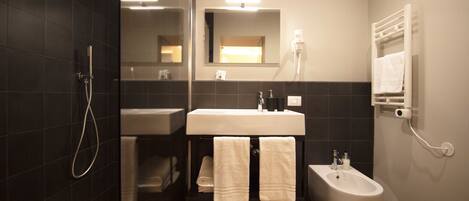 A modern bathroom with a glass-enclosed shower, a white sink, and a bidet.