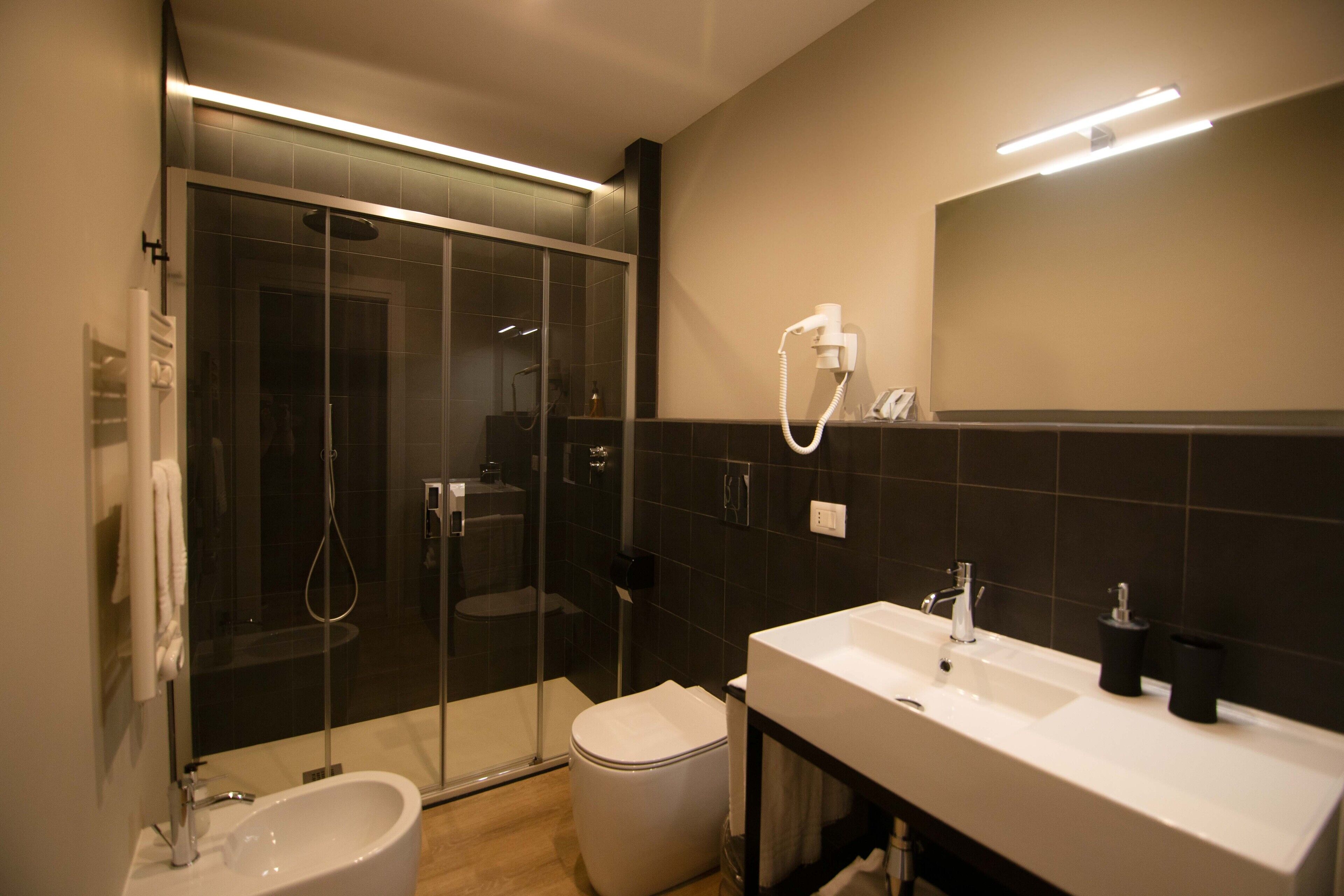 Un bany modern amb un envà de dutxa de vidre, un lavabo blanc i un mirall sobre el lavabo.
