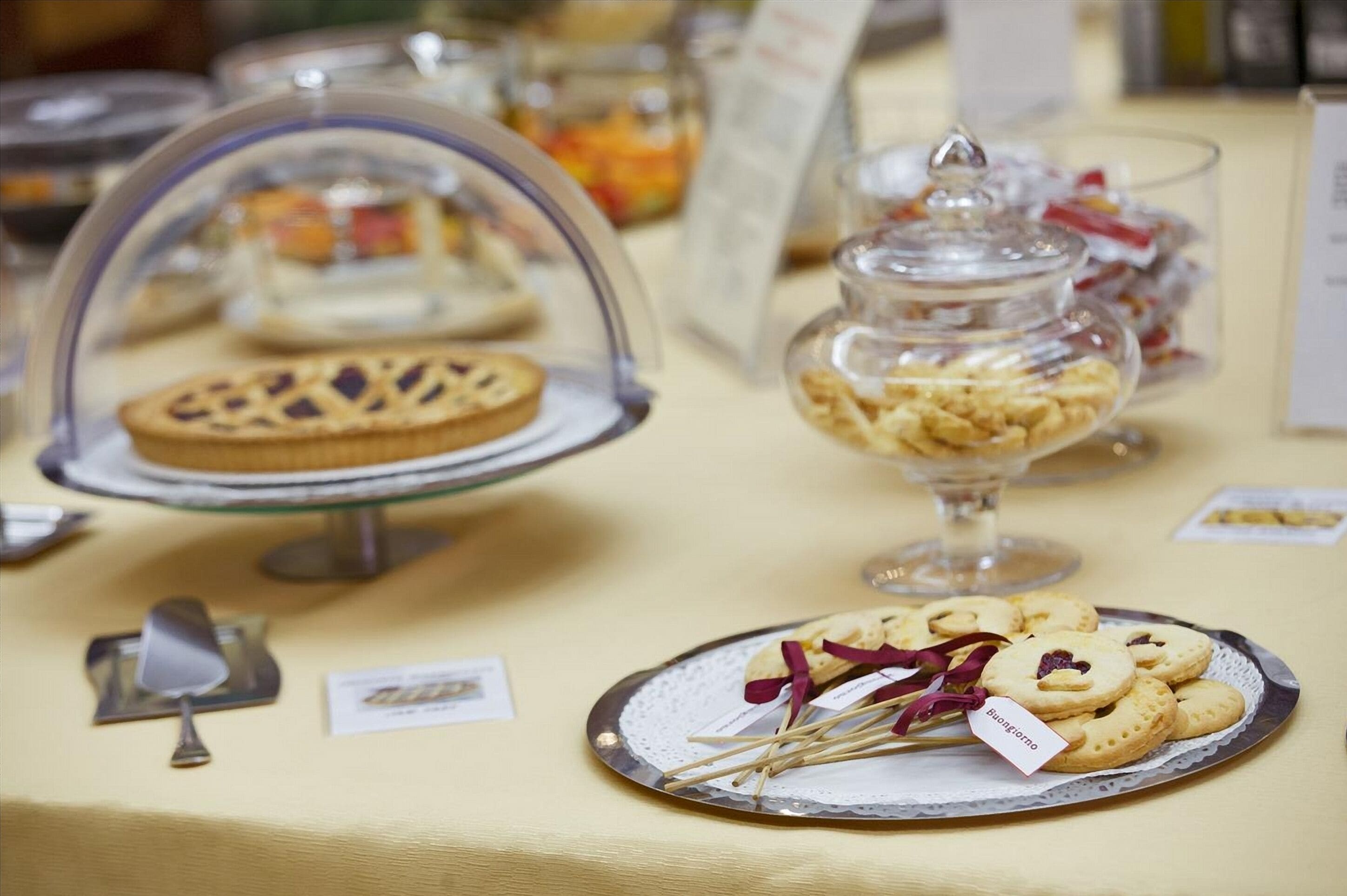 Una mesa de buffet con diversos postres expuestos en recipientes de vidrio y en platos.