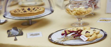 Una mesa de buffet con diversos postres expuestos en recipientes de vidrio y en platos.
