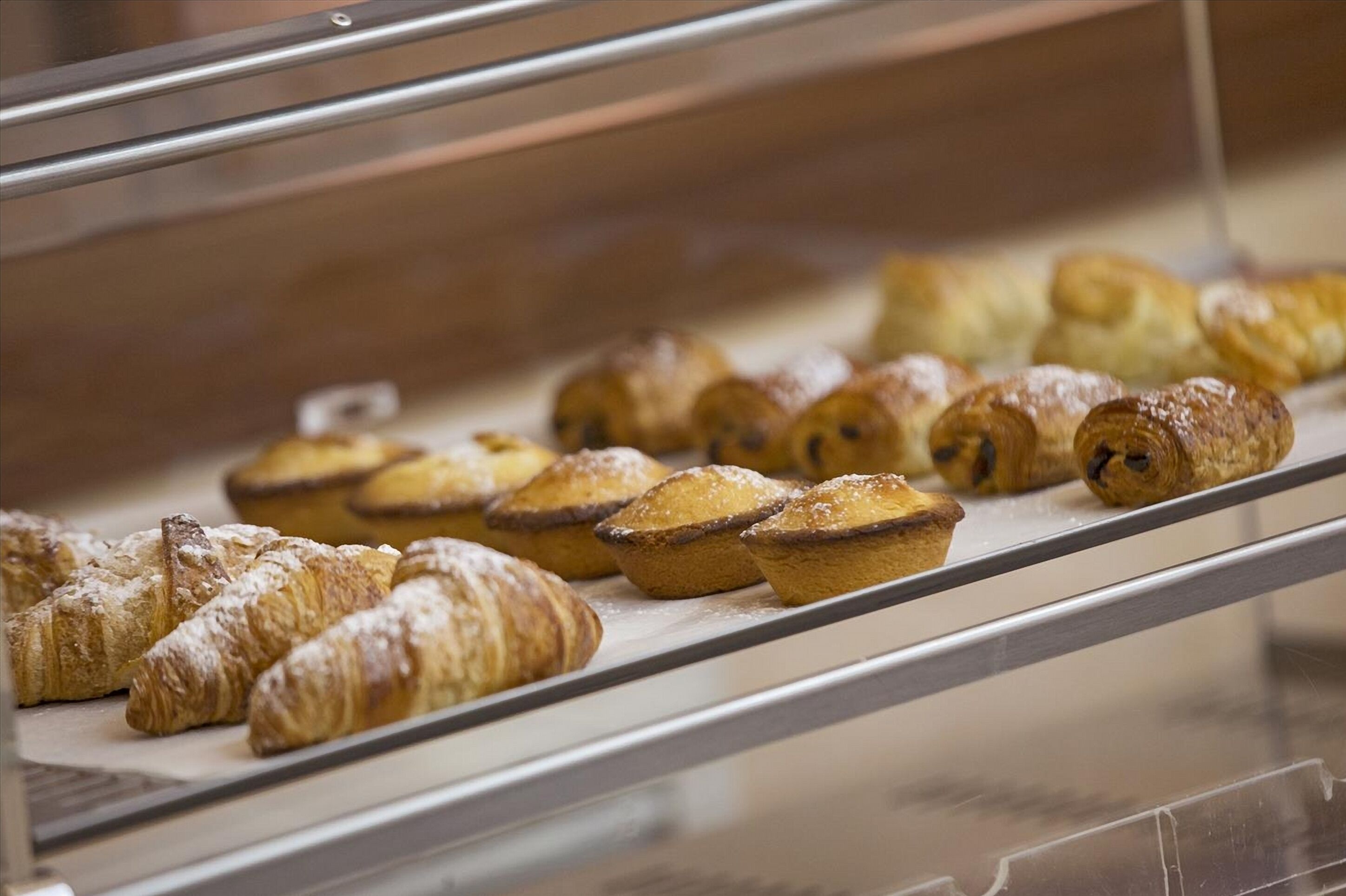 Une vitrine contenant divers produits de boulangerie, notamment des croissants et des muffins.