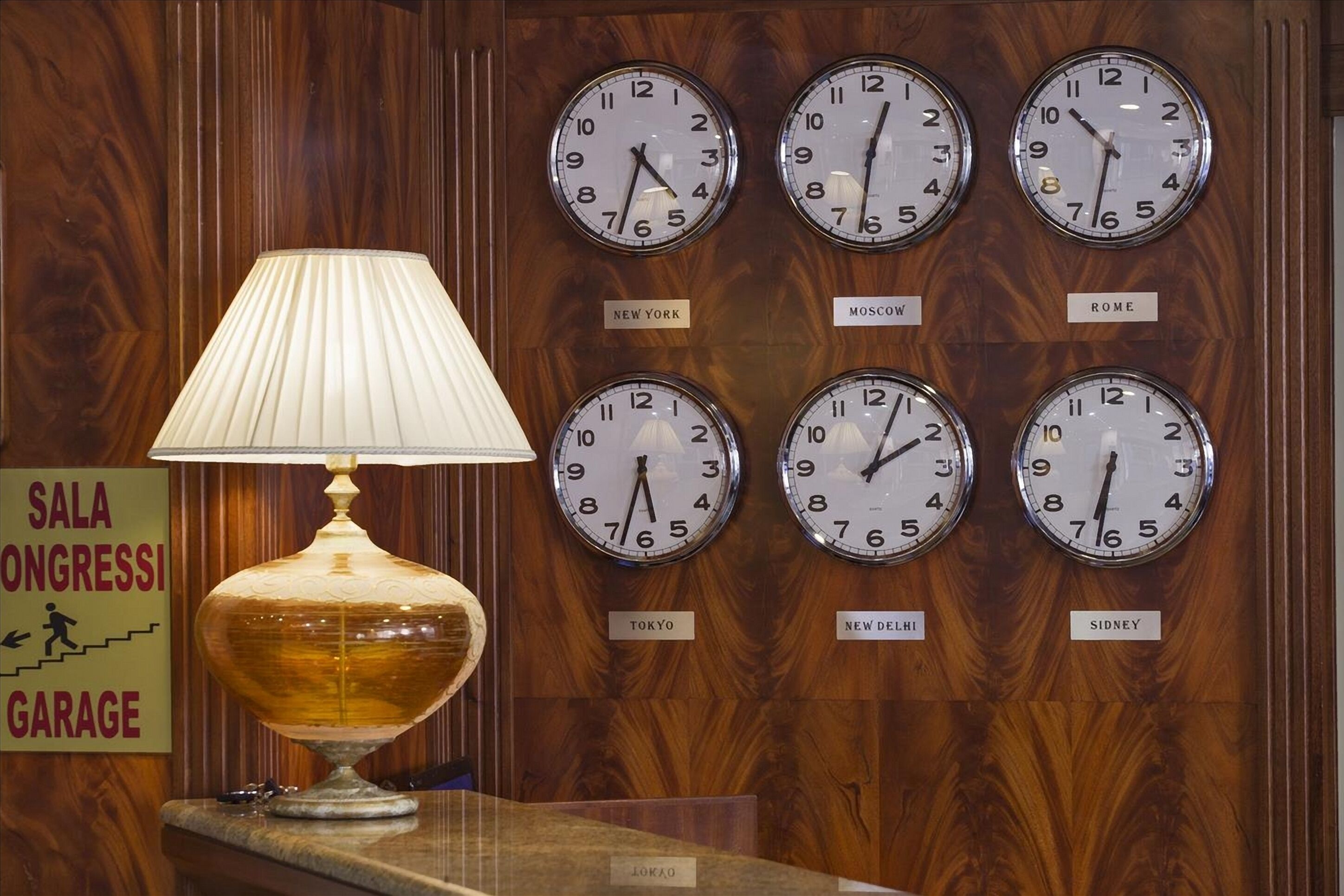 Un hall d’entrée avec un mur en bois où sont accrochées des horloges portant l’indication des noms de villes comme New York, Moscou et Tokyo.