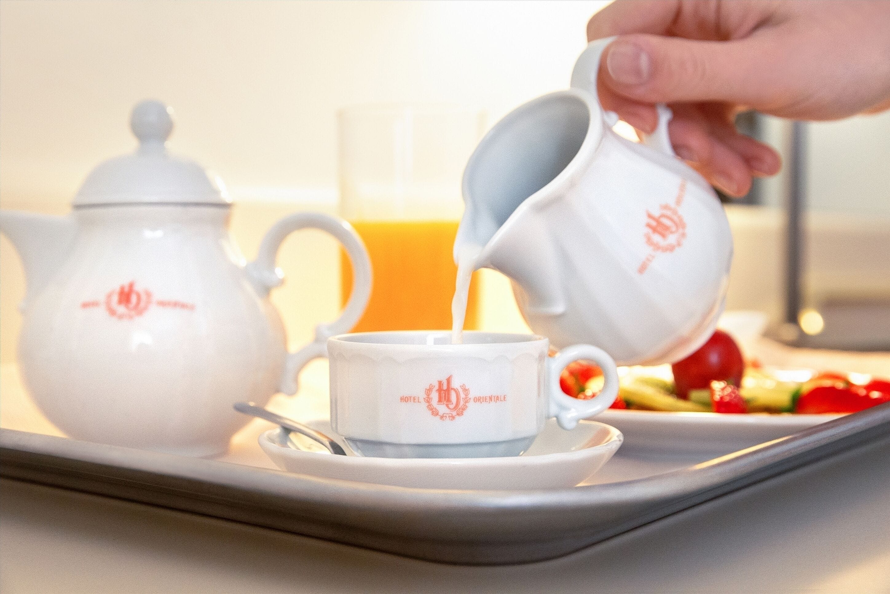 Un vassoio con un bollitore, una tazza e una brocca che viene riempita con una bevanda.