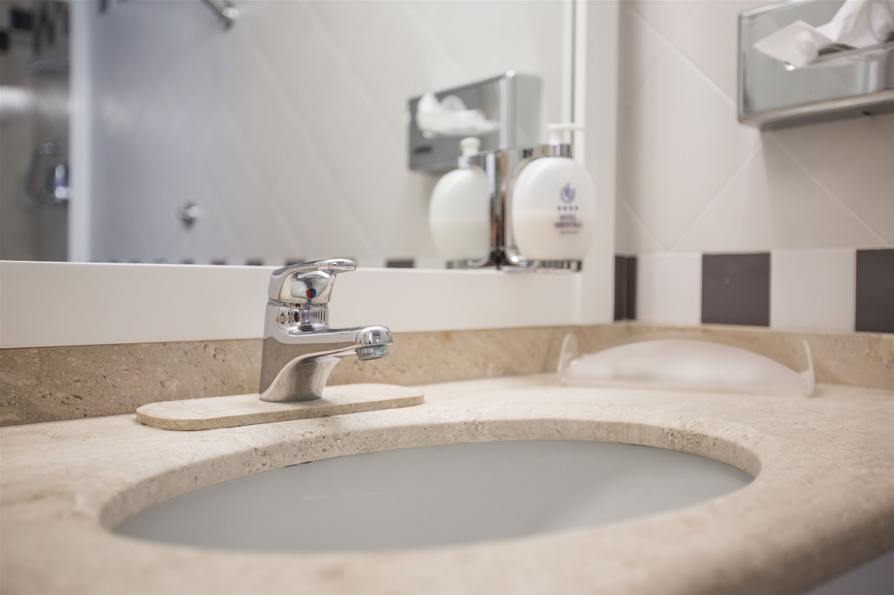 A bathroom sink with a modern faucet, a mirror, and a soap dispenser.