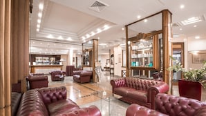 A spacious lobby with leather sofas, a bar area, and a large mirror reflecting the space.
