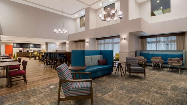 Un hall d’hôtel spacieux avec un canapé bleu, des chaises en bois et un coin repas.