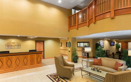 A hotel lobby with a reception desk, seating area, and a staircase.