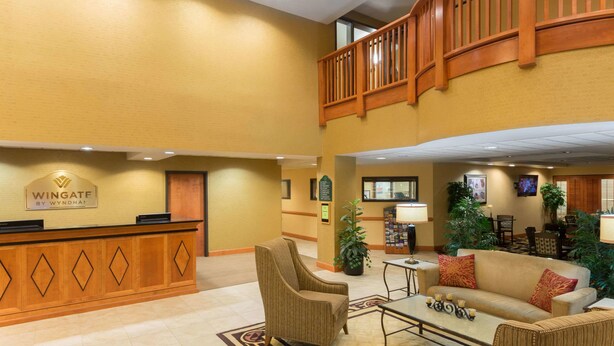A hotel lobby with a reception desk, seating area, and a staircase.