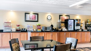 A modern kitchen with wooden cabinets, a glass-top dining table, and various appliances including a microwave, toaster, and refrigerator.