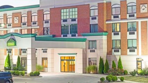A multi-story hotel with a brick facade, large windows, and a green awning.