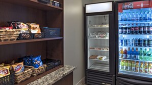 A snack display with chips and a beverage refrigerator stocked with various drinks. - Staybridge Suites Austin NW by IHG (Austin)