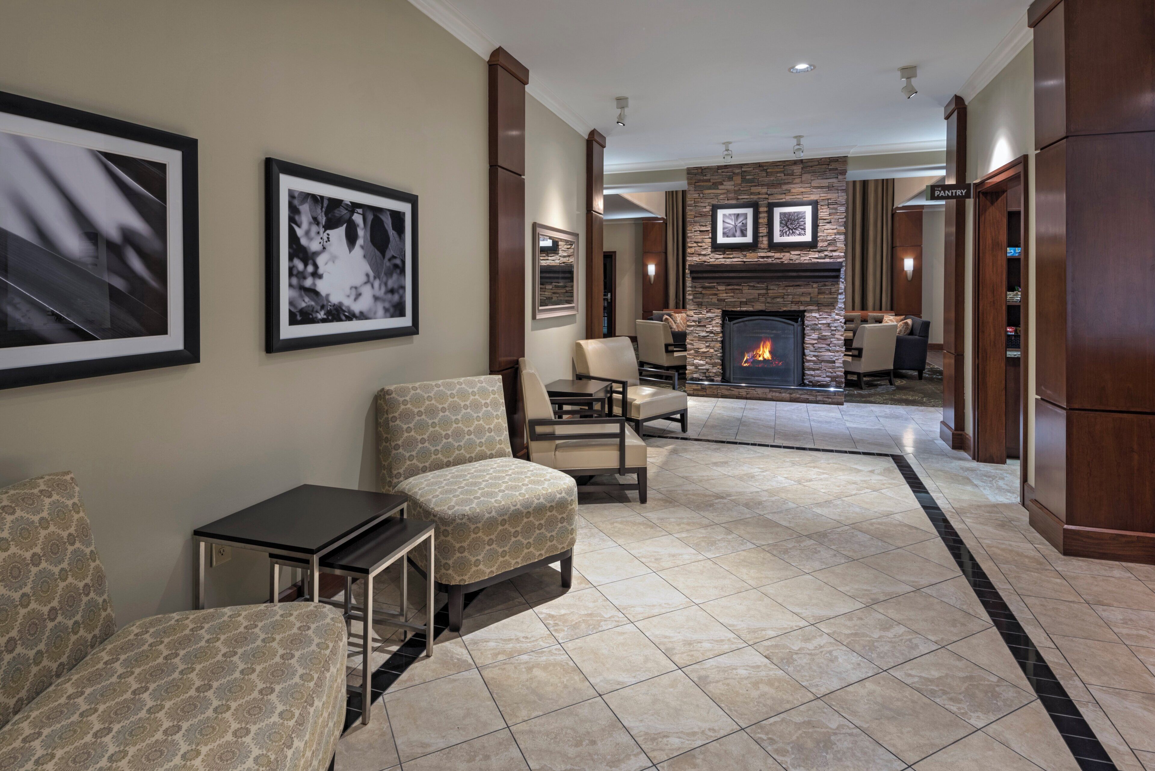 A hotel lobby with a fireplace, seating area, and framed artwork on the walls.