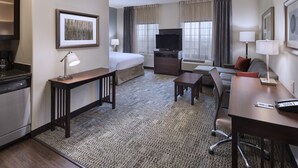 A hotel room with a bed, desk, chair, television, and a kitchenette. - Staybridge Suites Austin NW by IHG (Austin)