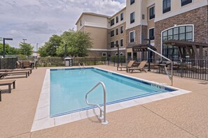 A rectangular pool with a metal ladder, surrounded by lounge chairs and a covered seating area. - Staybridge Suites Austin NW by IHG (Austin)