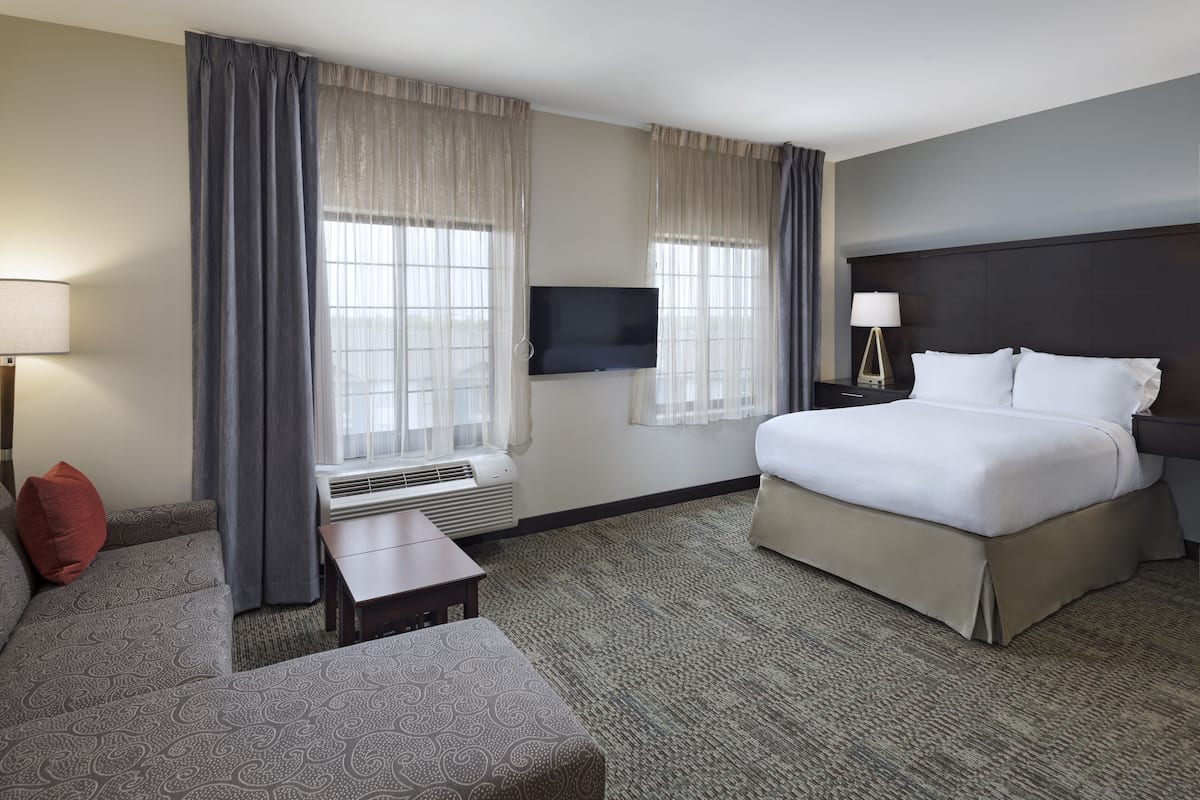 A hotel room with a bed, a TV, a desk, and a couch.