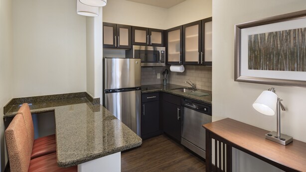 A compact kitchen with stainless steel appliances, a built-in microwave, and a dishwasher. - Staybridge Suites Austin NW by IHG (Austin)