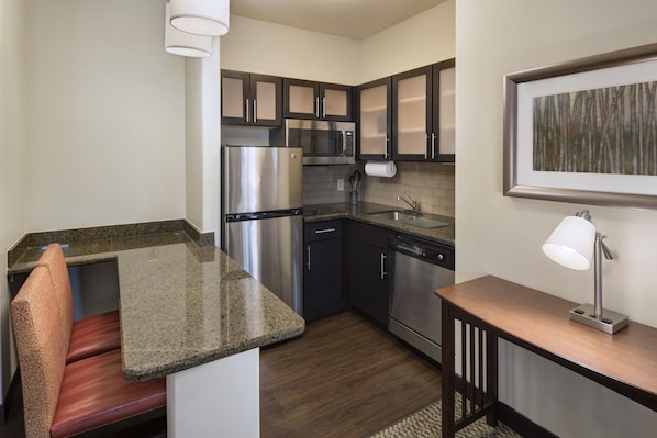 A compact kitchen with stainless steel appliances, a built-in microwave, and a dishwasher. - Staybridge Suites Austin NW by IHG (Austin)