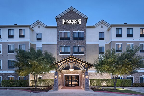 A Staybridge Suites hotel with a brick facade, multiple windows, and a central entrance with a canopy. - Staybridge Suites Austin NW by IHG (Austin)