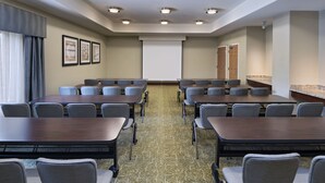 A conference room with multiple tables and chairs, a projector screen, and framed artwork on the walls. - Staybridge Suites Austin NW by IHG (Austin)
