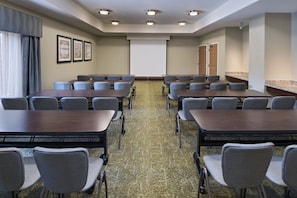 A conference room with multiple tables and chairs, a projector screen, and framed artwork on the walls. - Staybridge Suites Austin NW by IHG (Austin)