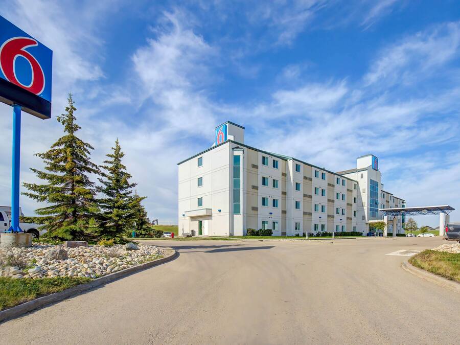 Un motel con un letrero grande, un estacionamiento y un edificio de varios pisos y ventanas.