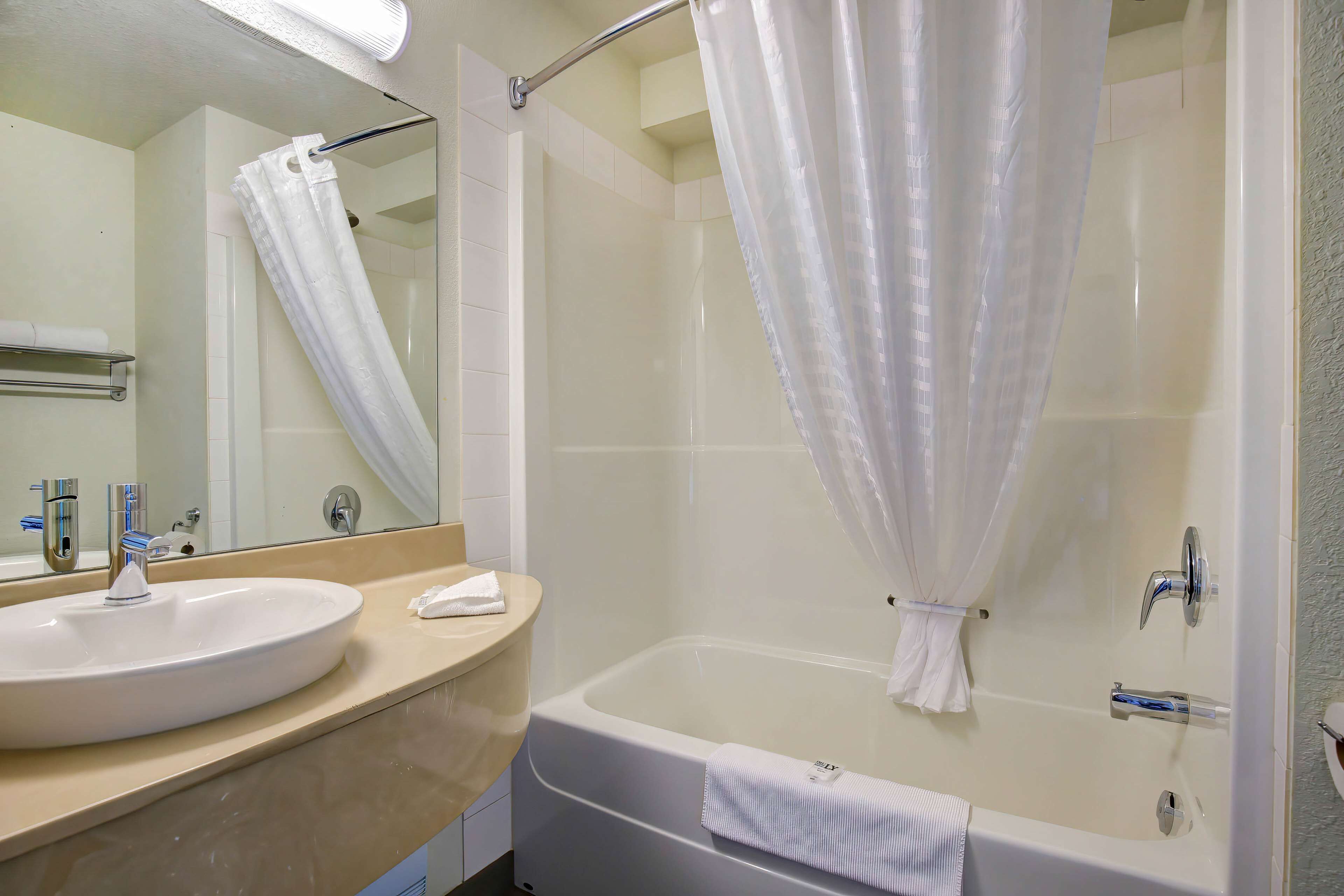 Ein Badezimmer mit Waschbecken, Spiegel, Badewanne und Duschvorhang.