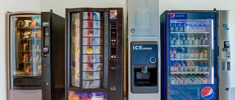 Four vending machines, including a Pepsi refrigerator and an ice dispenser, in a commercial setting.
