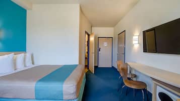 Ett hotellrum med en säng, ett skrivbord, en stol och en mikrovågsugn.