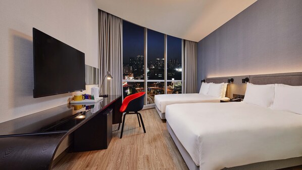 A hotel room with a bed, a desk with a flat-screen TV, a chair, and a city view through large windows. - Holiday Inn Express Taichung Park by IHG (Taichung)
