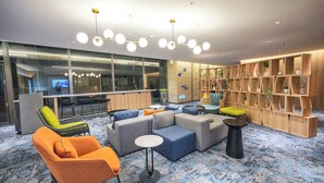 Uma área de estar moderna com sofás, uma mesa redonda e uma estante.