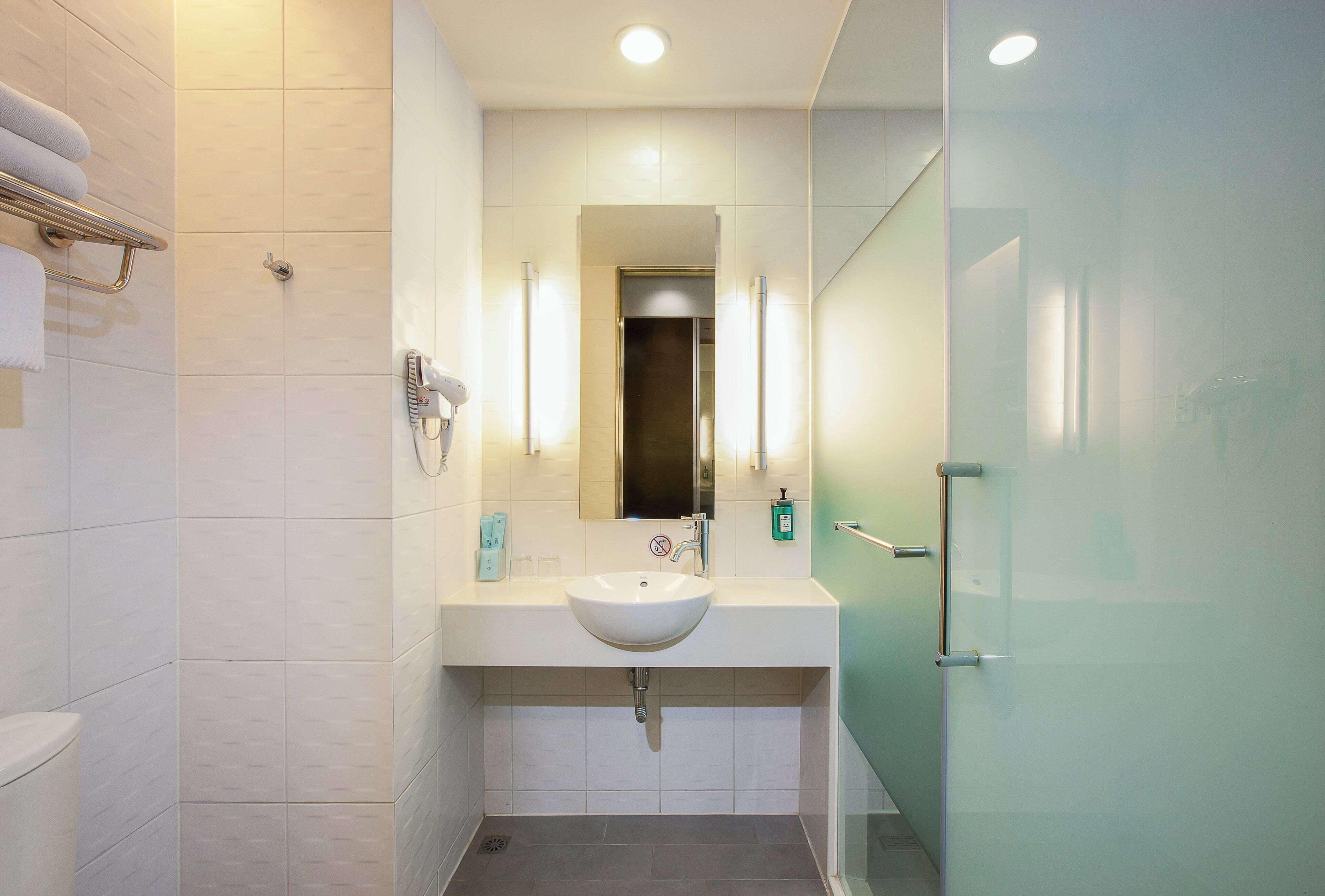 A modern bathroom with a white sink, mirror, and towel rack.