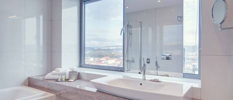 A modern bathroom with two sinks, a large window, and a view of the city.