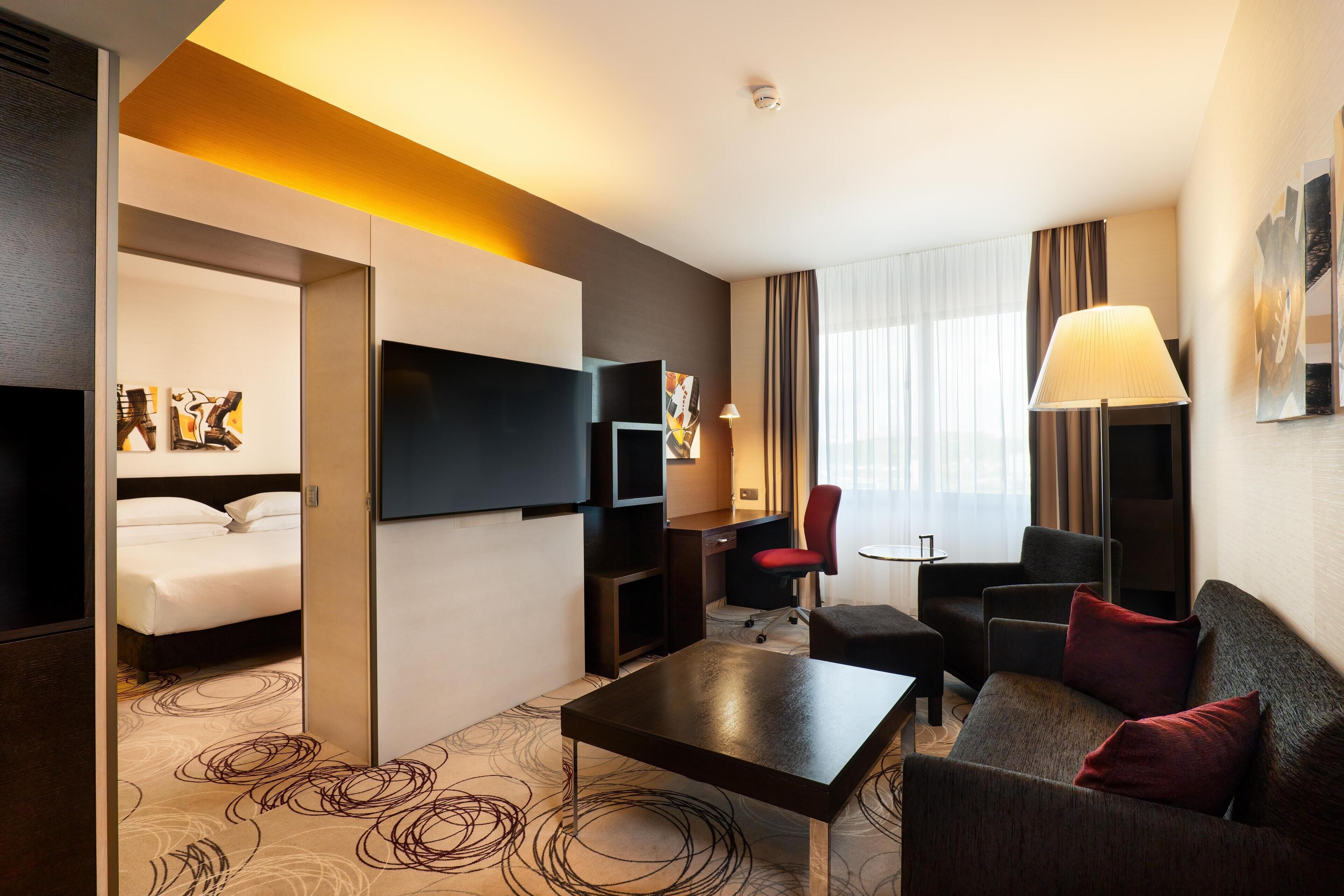 A hotel room with a bed, a TV, a desk, a sofa, and a coffee table.