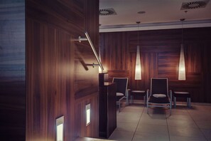 A modern waiting area with wooden paneling, a reception desk, and two chairs. - DoubleTree by Hilton Hotel Kosice (Kosice)