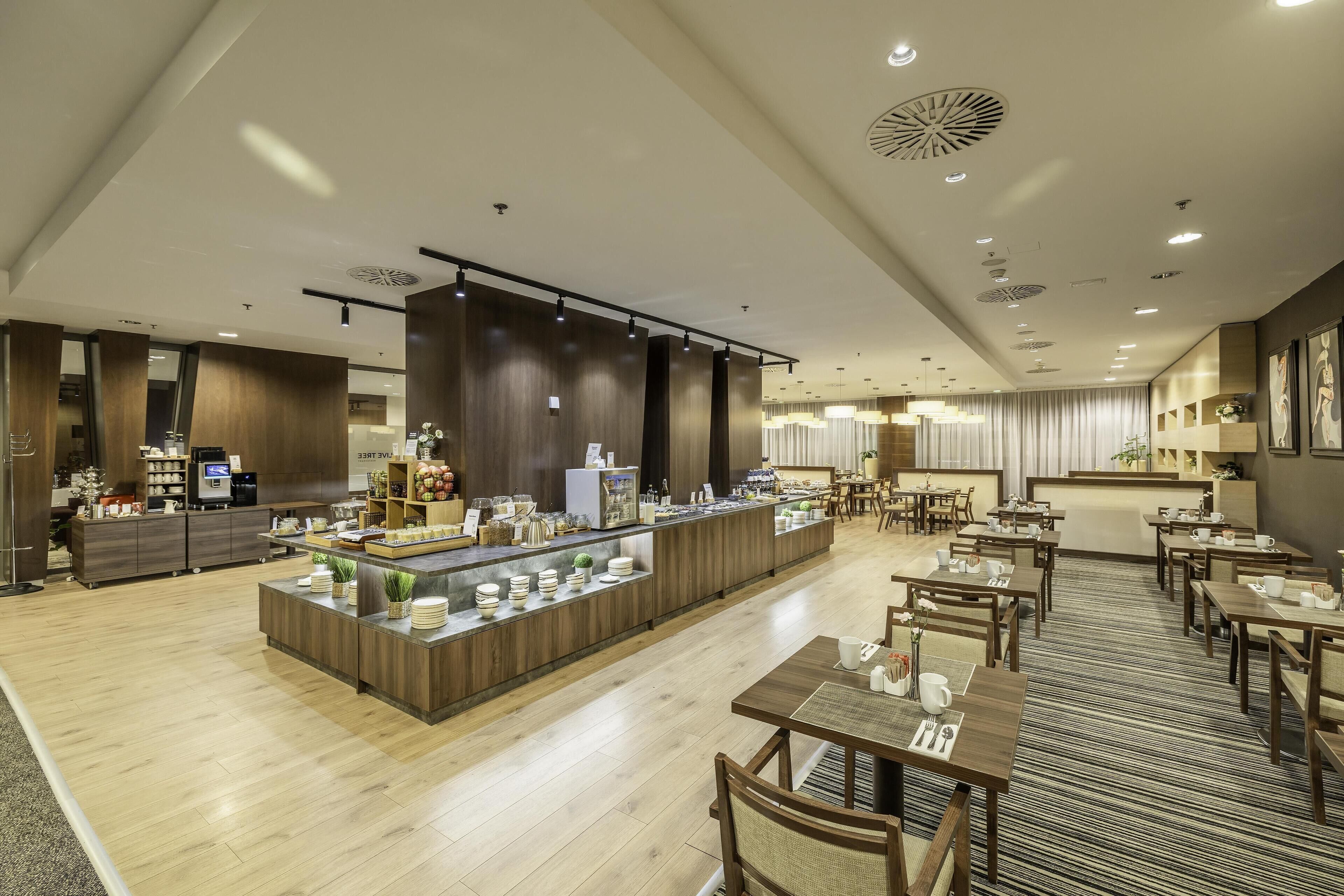 Un moderno vestíbulo de hotel con una zona de bar central, mesas de comedor y una recepción.