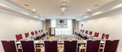 A conference room with a long table, red chairs, and a podium.