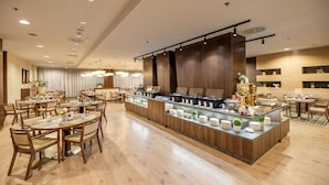 A spacious hotel lobby with multiple dining tables and a central buffet area.
