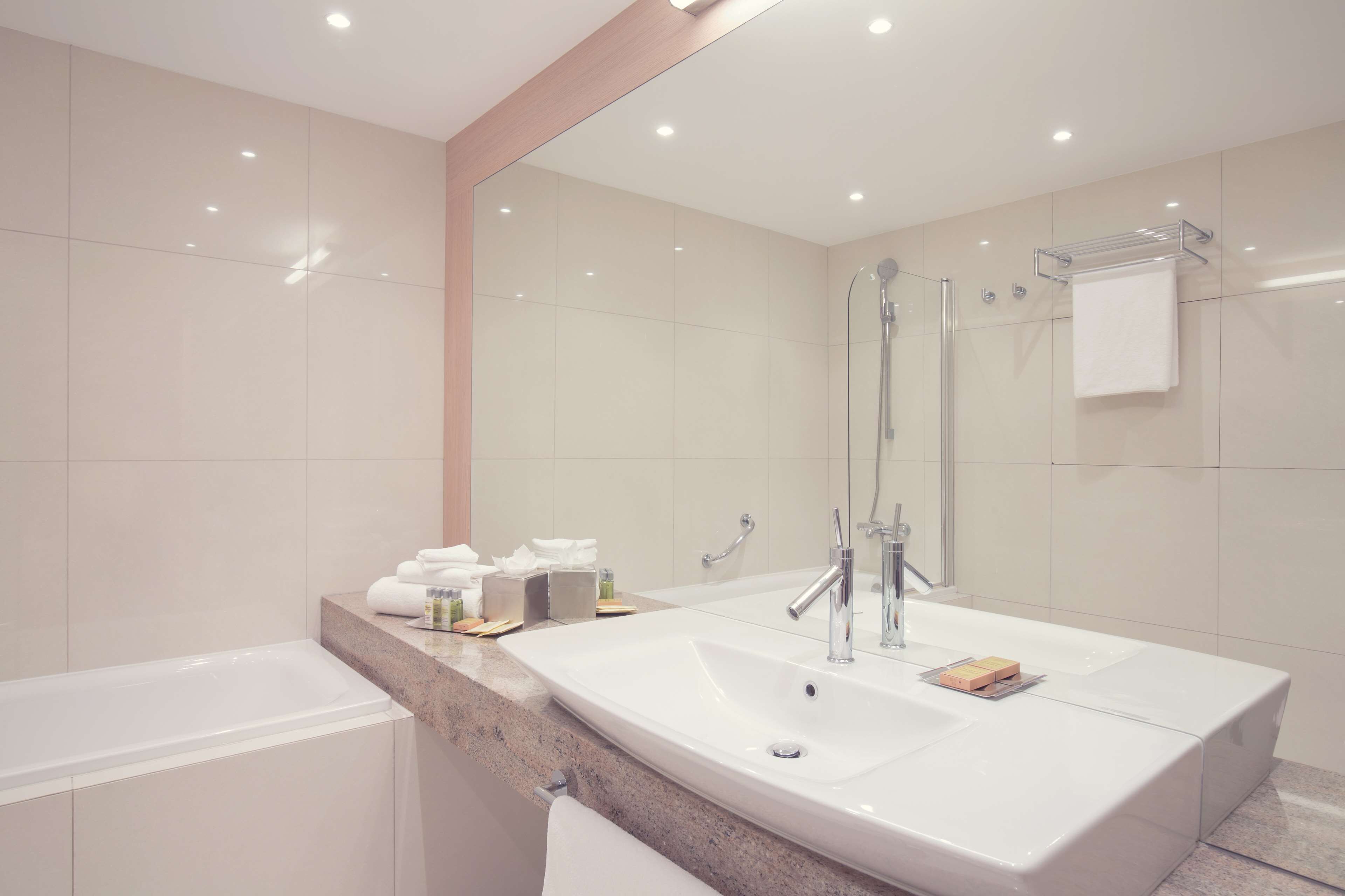 A modern bathroom with a large sink, a glass shower enclosure, and a mirror.