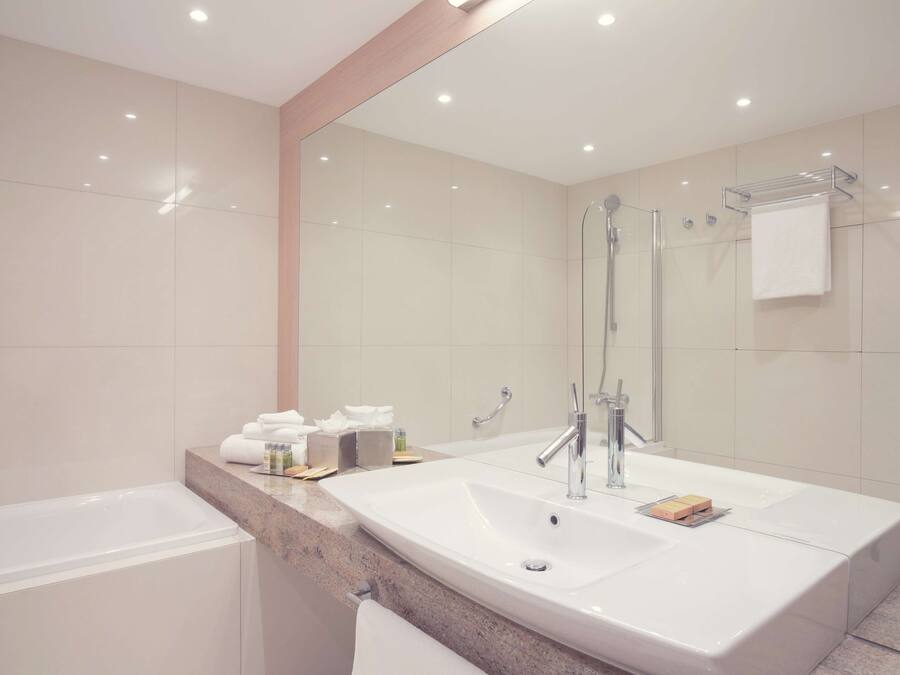 A modern bathroom with a large sink, a glass shower enclosure, and a mirror.