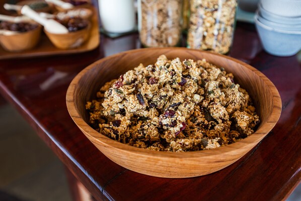 A wooden bowl filled with granola on a wooden table.