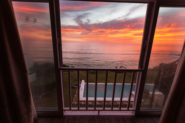 A balcony with a view of the ocean during sunset.