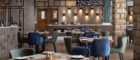 A restaurant with multiple tables and chairs, a stone pillar, and a wall with a geometric pattern.