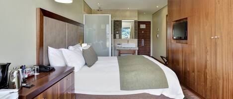 Habitación de hotel con una cama grande, armario de madera, un escritorio con teléfono y televisor montado en el armario.