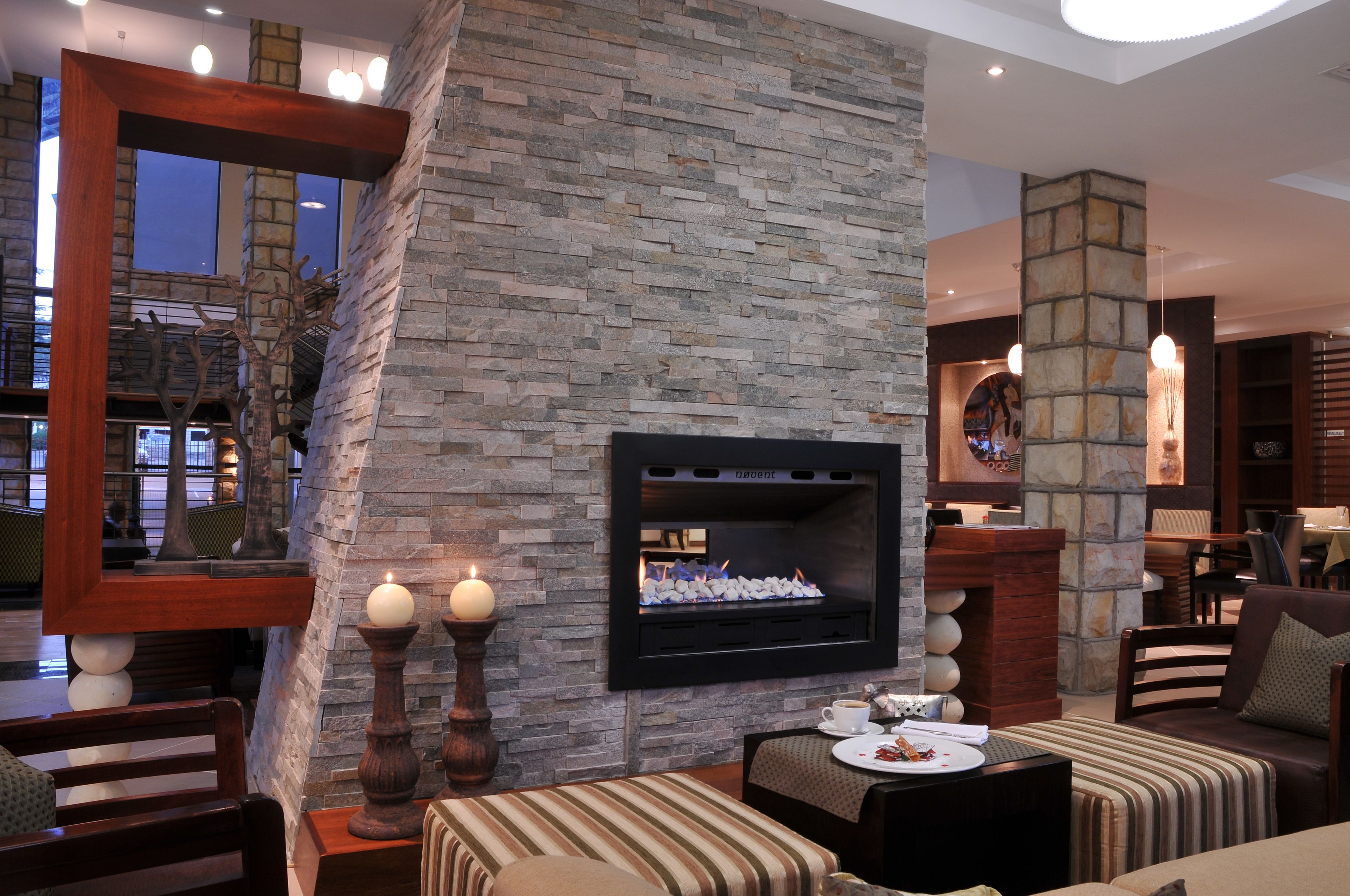 A modern interior with a stone wall, a fireplace, and seating areas.