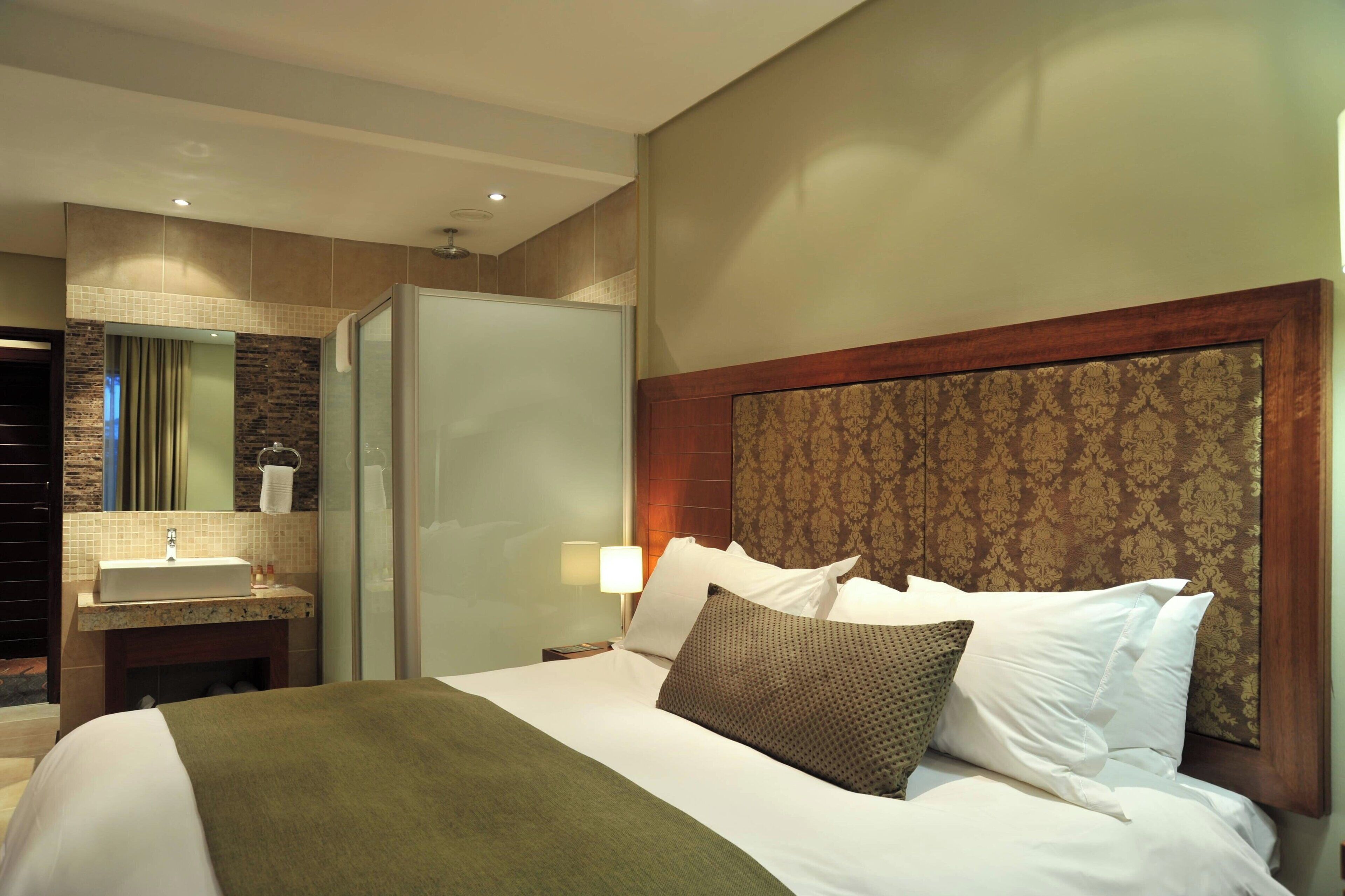 A hotel room with a bed, a bathroom with a sink, and a mirror.