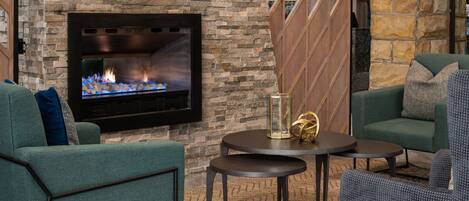 Una sala de estar acogedora con una pared de piedra, una chimenea y muebles modernos.
